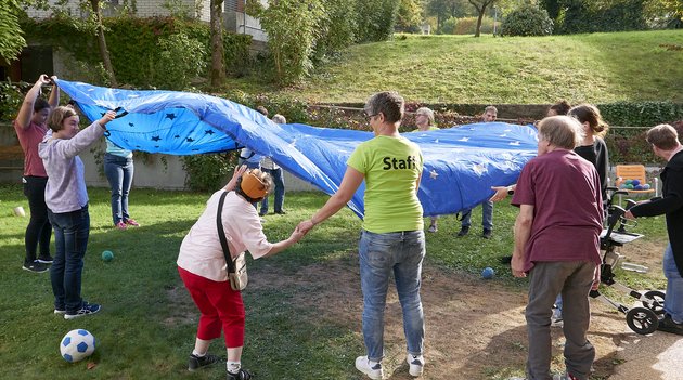 Mehrere Menschen spielen mit dem Fallschirm