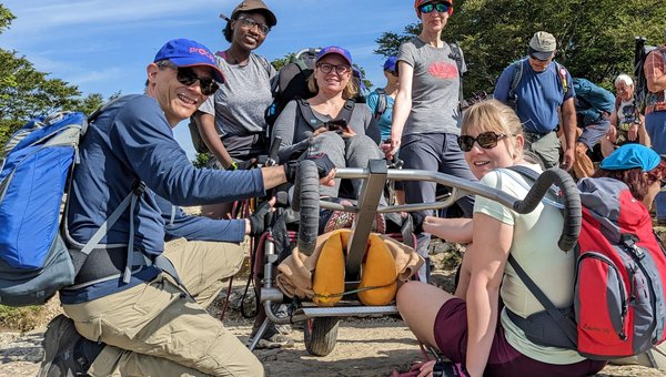 Eine Gruppe von Menschen und eine Person sitzt in einem Trekkingrollstuhl