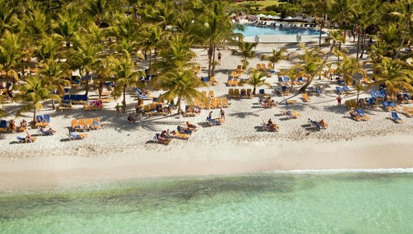 Wunderbarer Sandstrand mit vielen Palmen, Pool und Hotel im Hintergrund