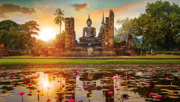 Ein Teich mit Blumen und im Hintergrund eine grosse Buddha-Statue.